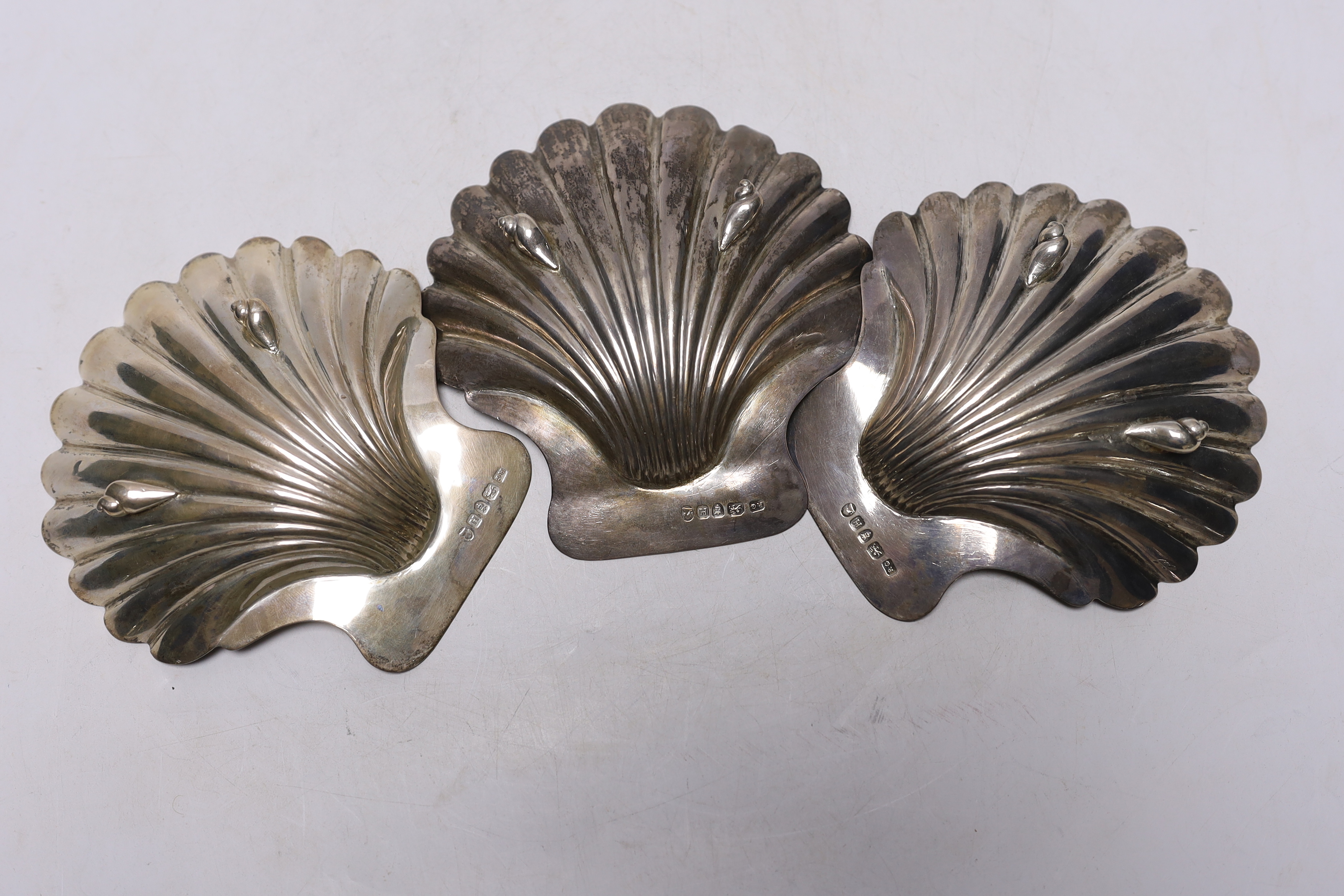 A set of three George III silver butter shells, each with engraved crest and on two shell feet, by Robert Garrard I, London, 1803, 12.8cm, 9.7oz.